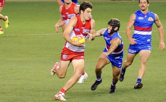 George Hewett of the Sydney Swans evades a tackle from the Bulldogs Caleb Daniel in an AFL game