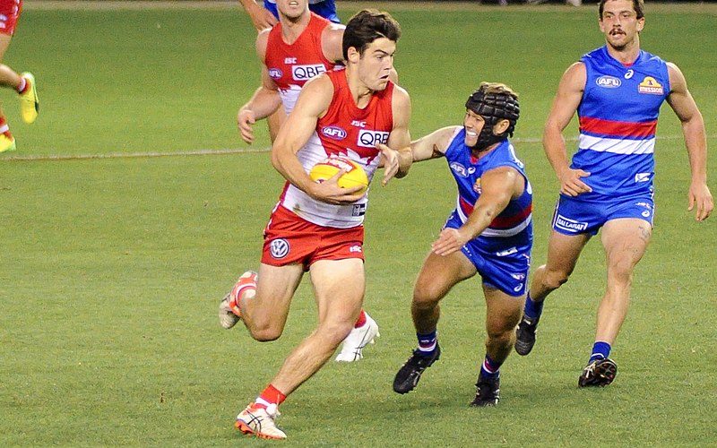 George Hewett of the Sydney Swans evades a tackle from the Bulldogs Caleb Daniel in an AFL game